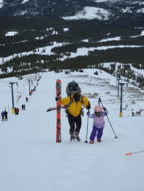 Father and daughter climbing mountain with skiis